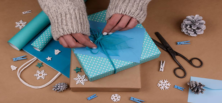 close up woman hands packing and wrapping gift box